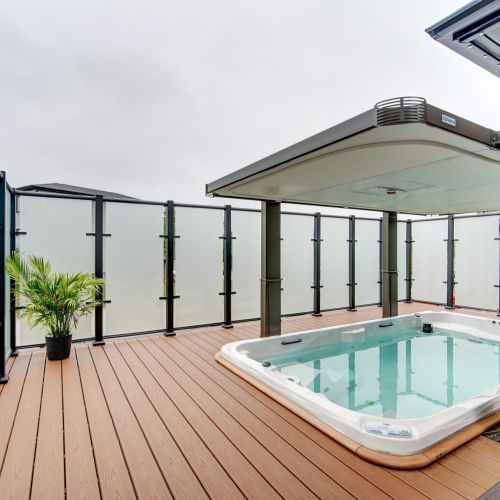 Hot tub with tall privacy glass and wind screen by DekSmart at 4 Crownridge Drive