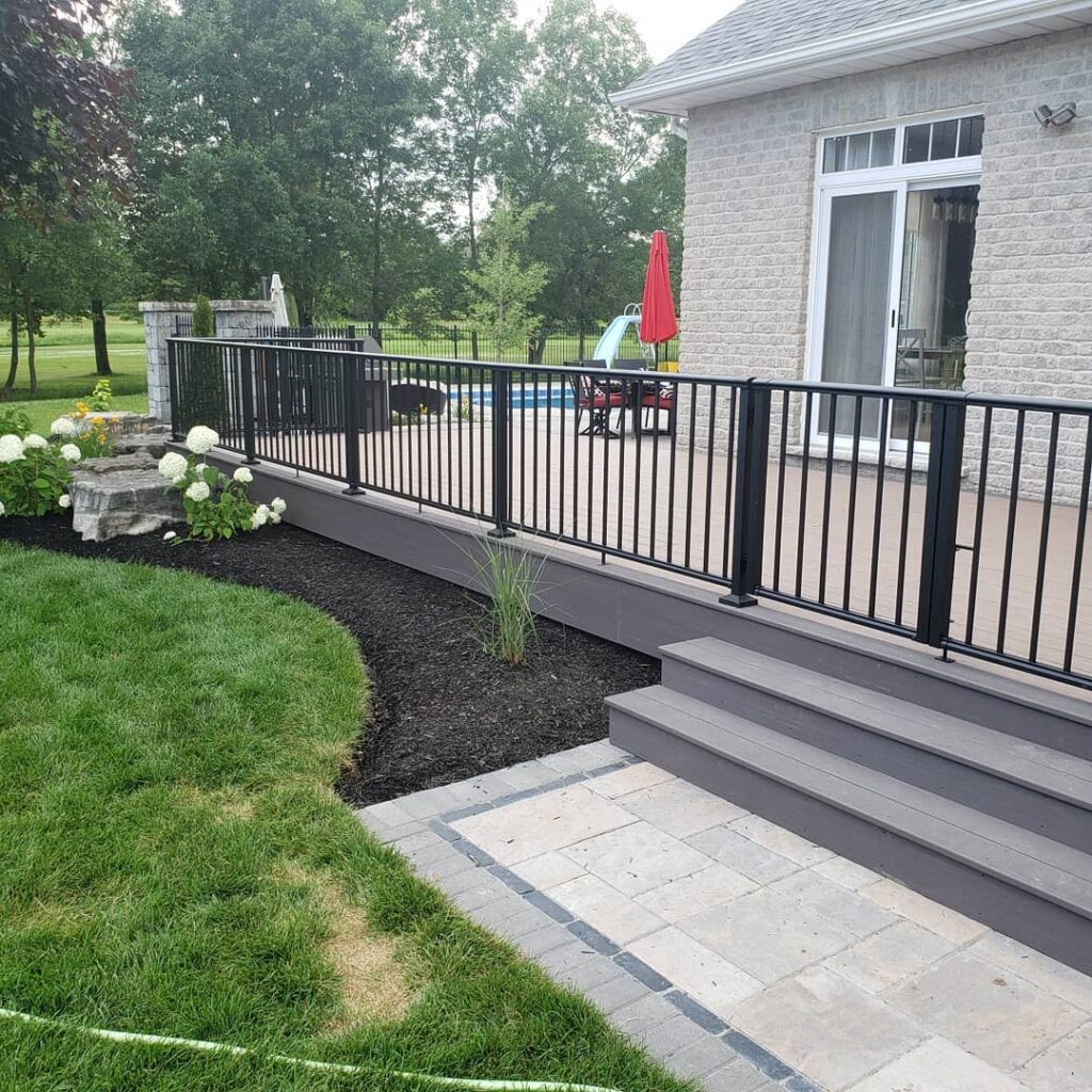 Black aluminum square picket railing installed around a swimming pool and side yard for Landtech in Belleville Ontario, Canada